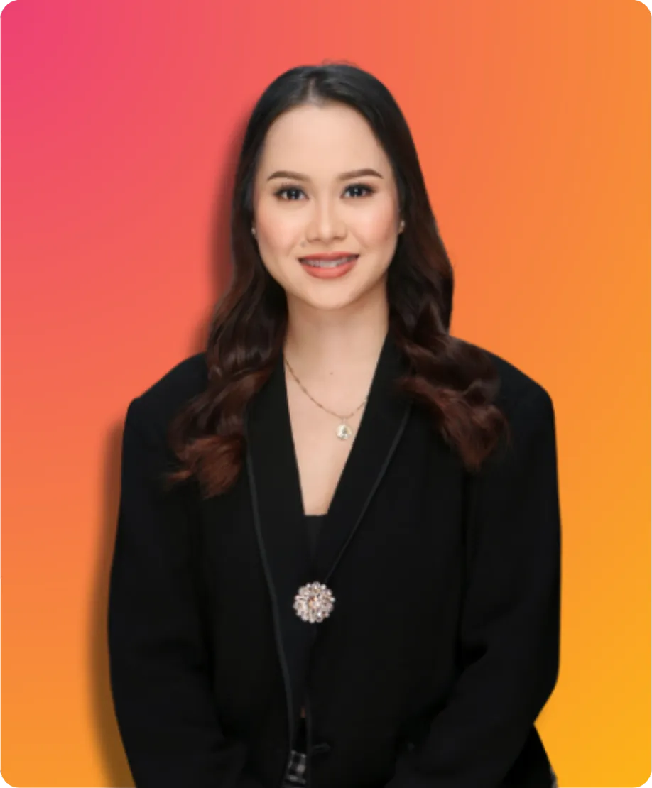 Young professional woman with long dark hair, wearing a black blazer and a delicate pendant necklace.